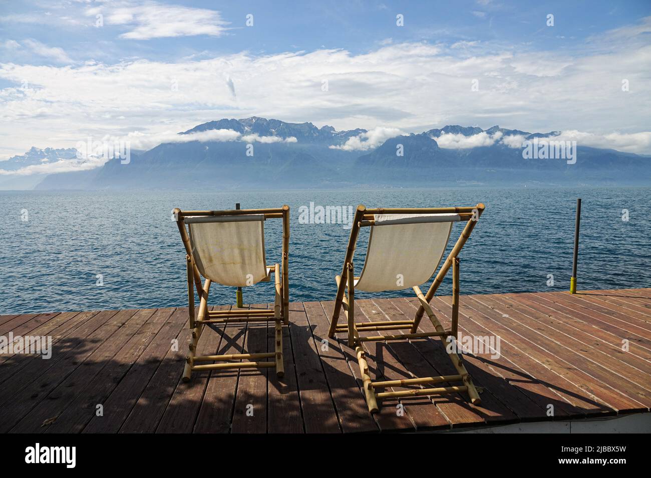 Two deckchairs on a wooden pontoon in front of a calm lake Stock Photo ...