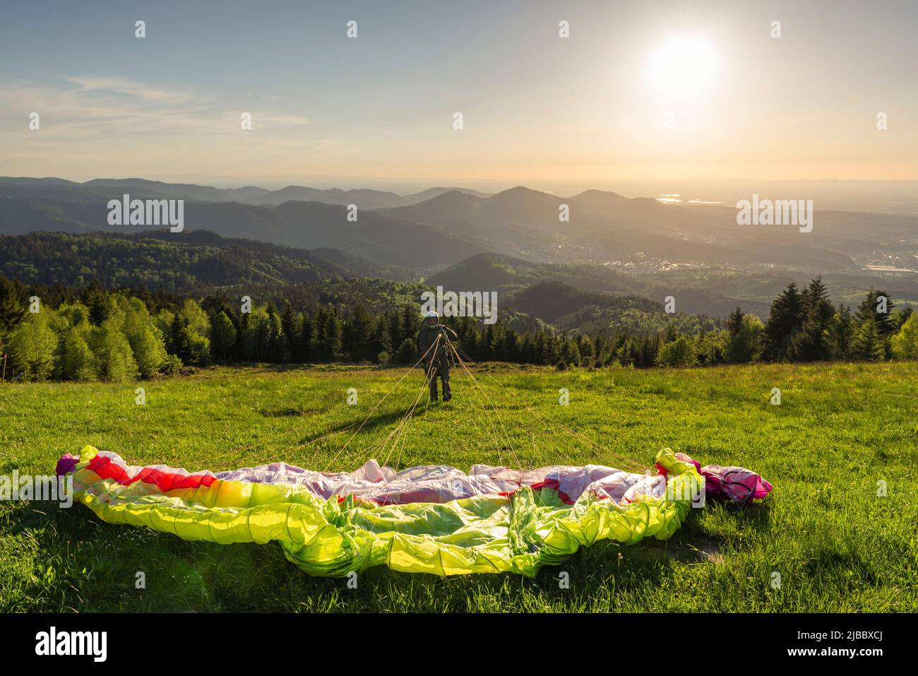 Paraglider at the take-off site at the Devil's mill in the Murg valley in the Black Forest spreads his paraglider against the afternoon sun, Germany Stock Photo