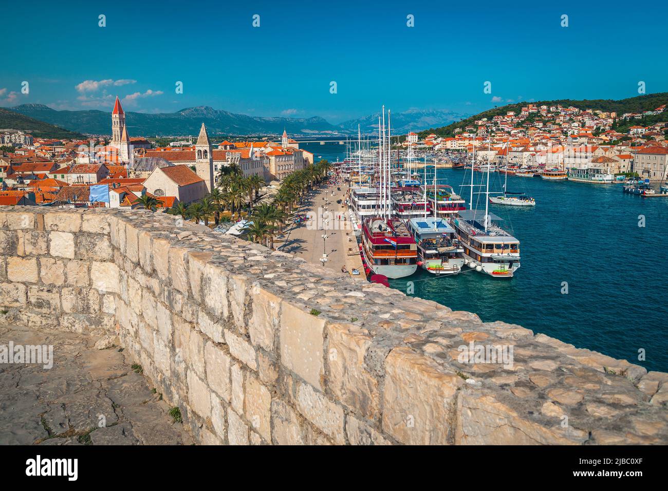 Great touristic location and beautiful view from the Kamerlengo castle. Walkway with palm trees, cozy street cafes and restaurants. Anchored boats and Stock Photo