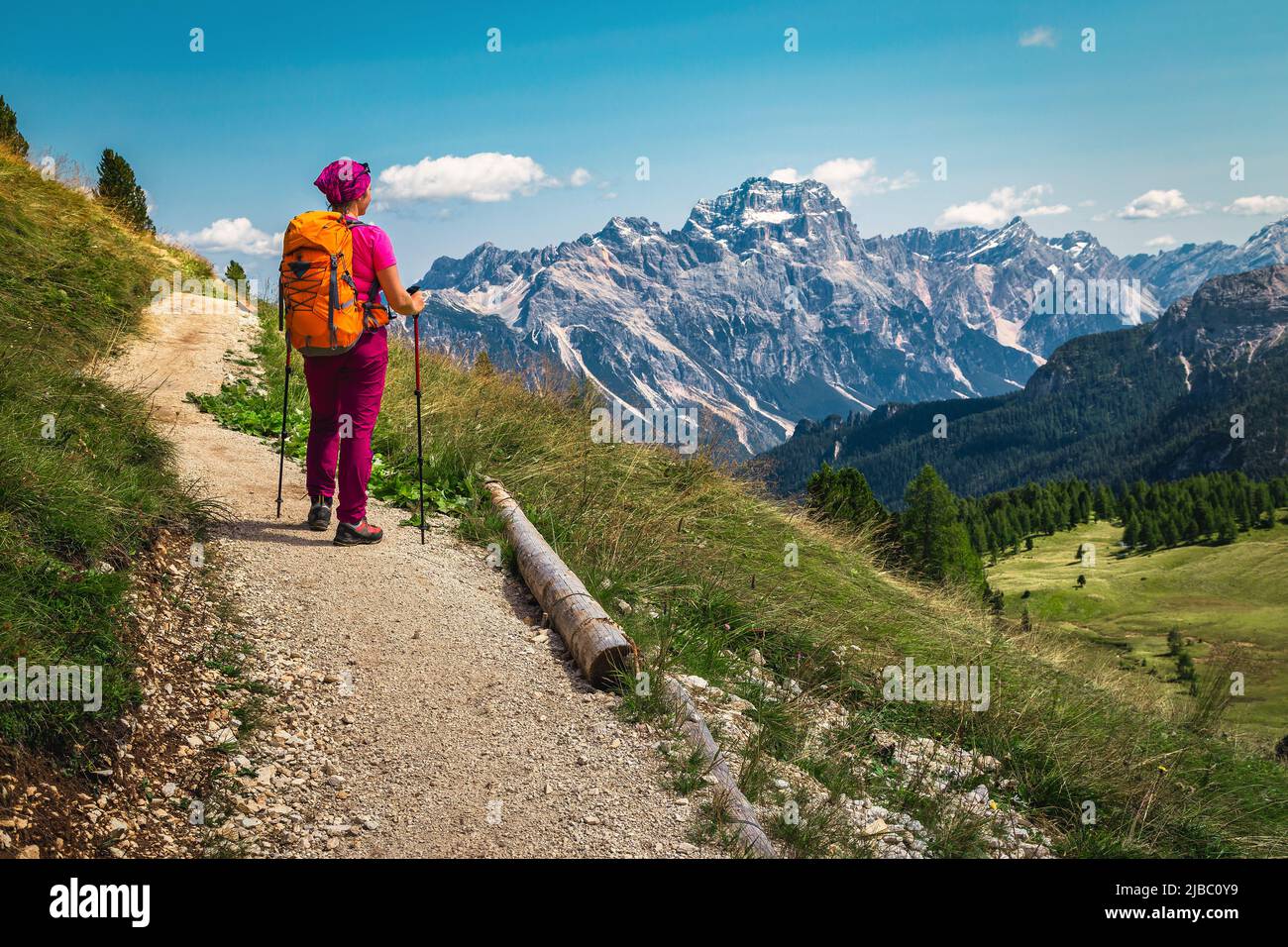 Sporty active woman hiker with colorful backpack and mountain equipment enjoying the view from the alpine trail, Dolomites, Italy, Europe Stock Photo
