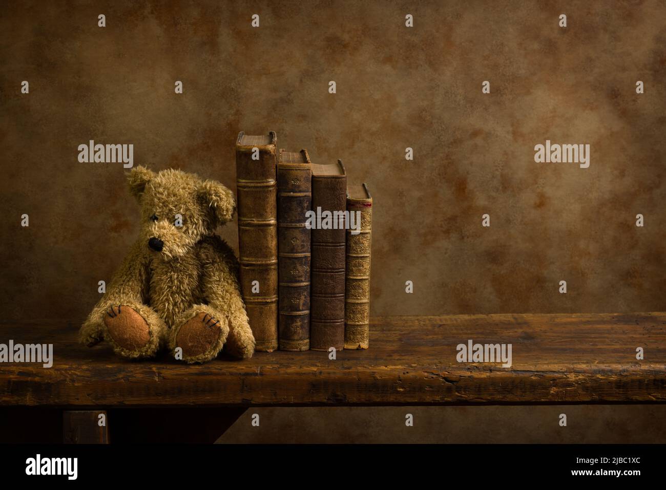Vintage teddy bear and antique books on a rustic old wooden shelf. This is suitable for digital compositing. Stock Photo