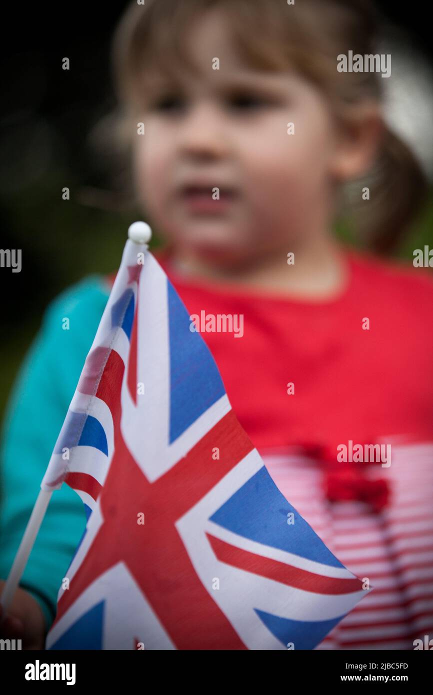 Little girl waving a British union flag in the crowd for the Queen's Platinum Jubilee Stock