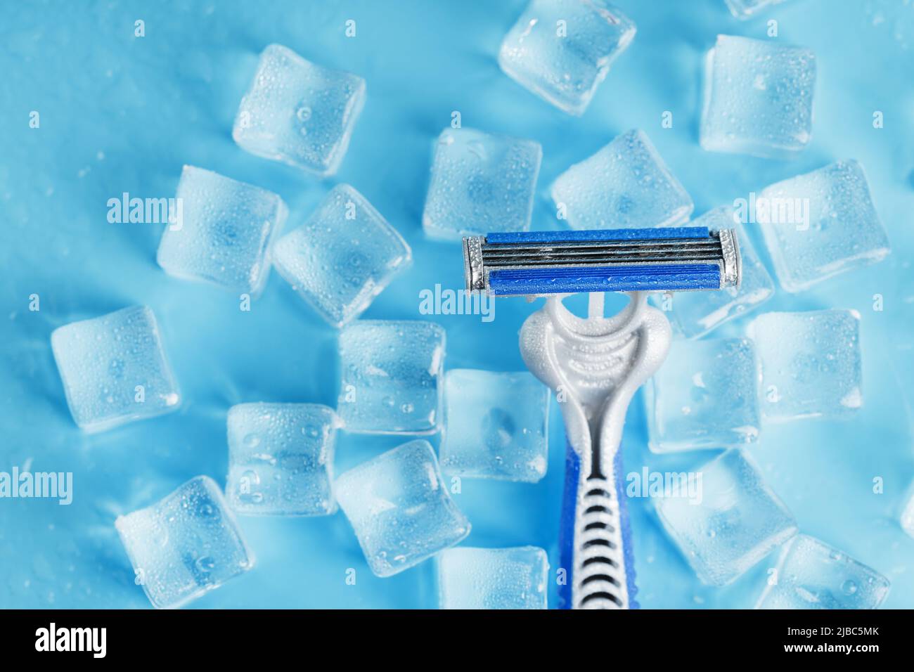 Shaving machine on a blue background with ice cubes. The concept of cleanliness and frosty freshness Stock Photo