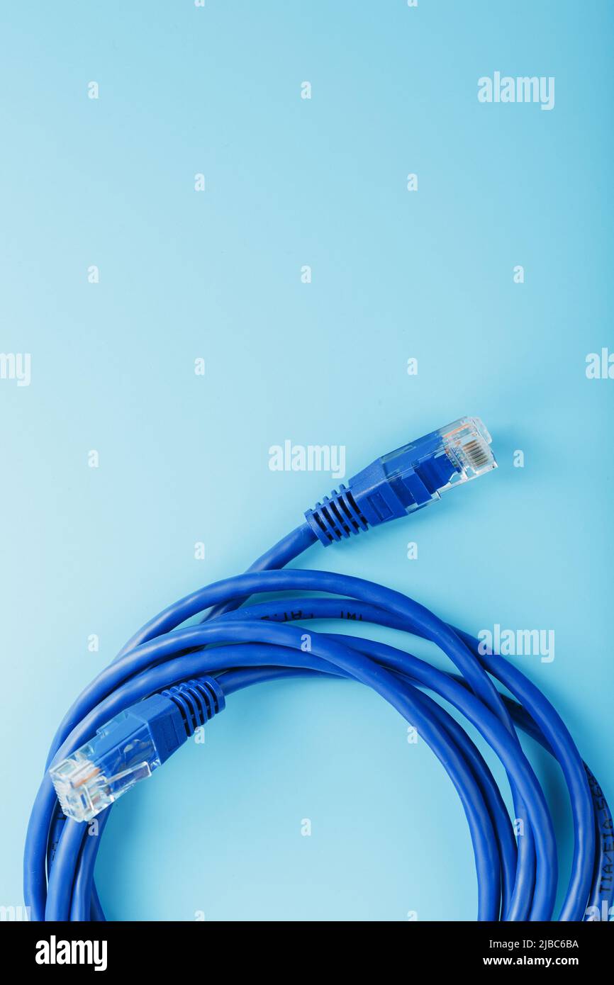 A coil of RJ45 Cat.6 Ethernet Network Internet Cable isolated on a blue background with free space Stock Photo