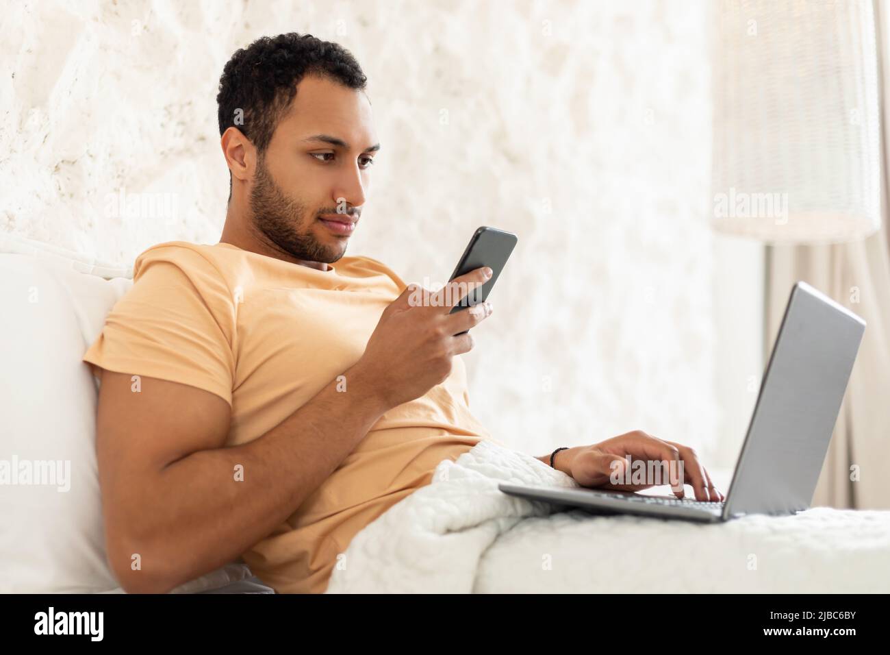 Honeguy Using Internet Arabic Guy Using Laptop And Cellphone Sitting In Bed Indoor Stock Photo ...