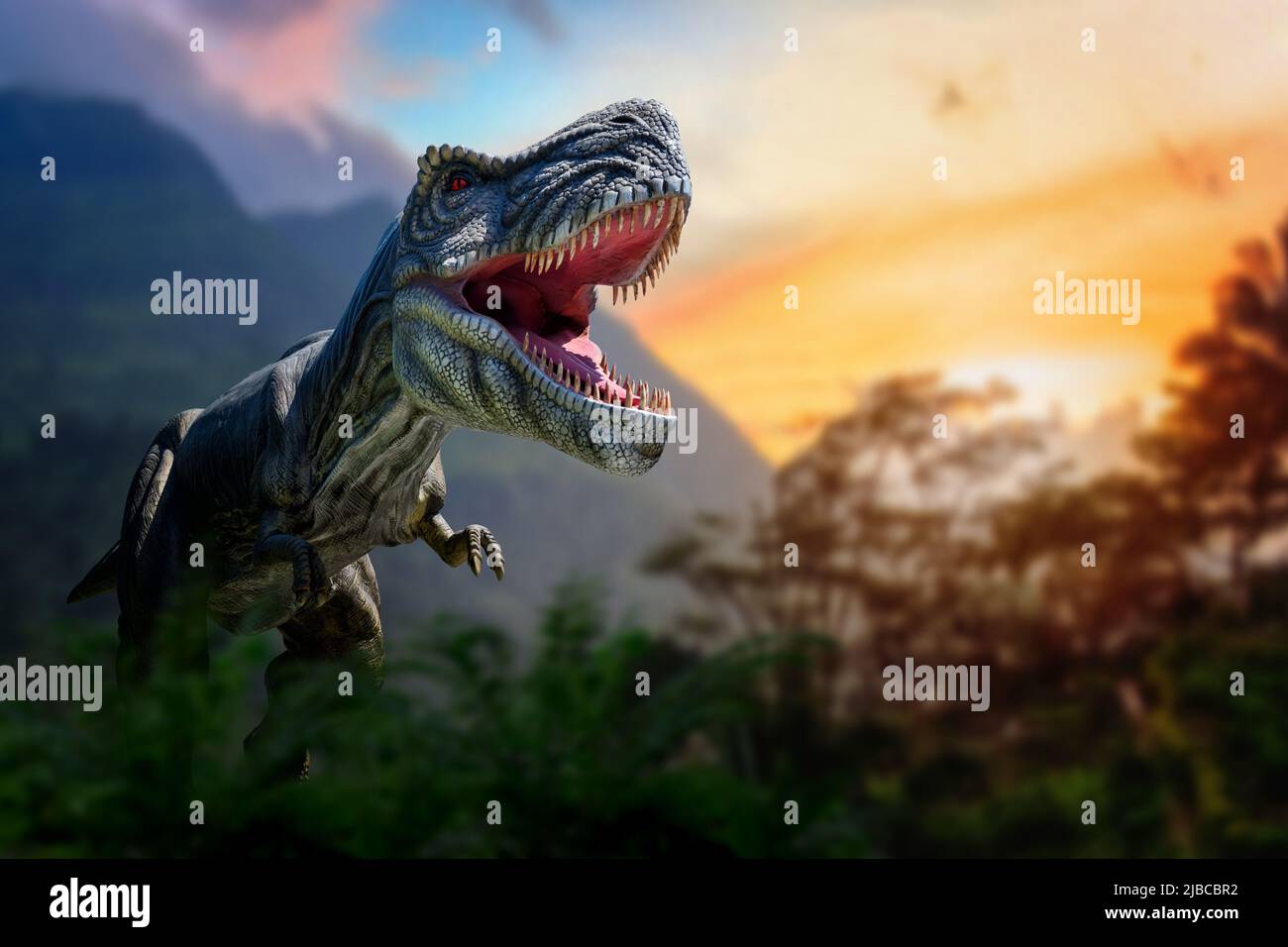Tyrannosaurus Rex in the jungle. Huge dinosaur against the mountain background of a prehistoric forest at sunset Stock Photo