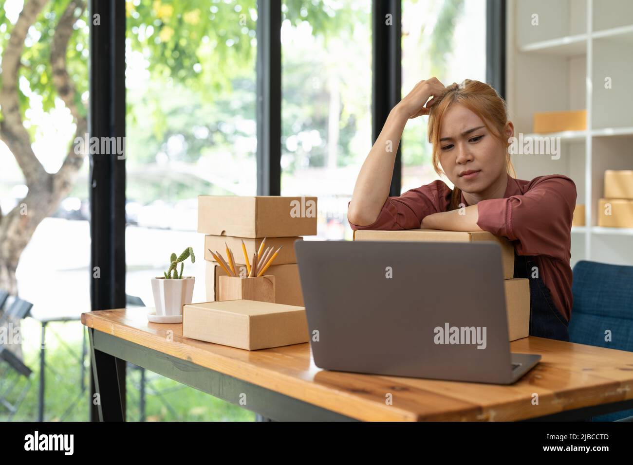 Asian woman think hard serious working laptop computer at home selling ...