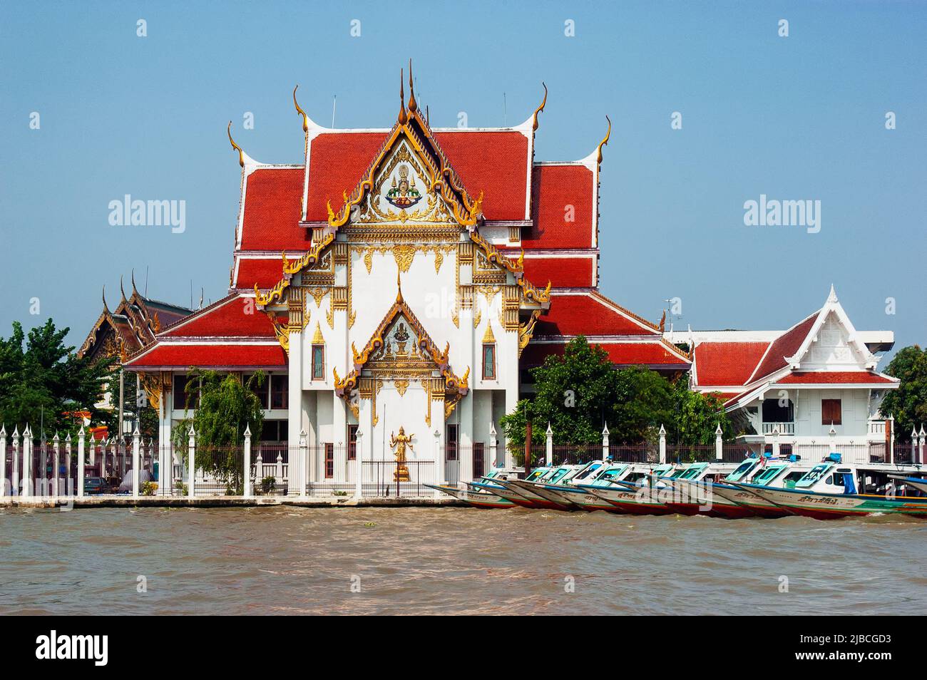 Wat Rakhang, the bell temple by the Chao Phraya River, Bangkok, Thailand with a line of boats moored Stock Photo