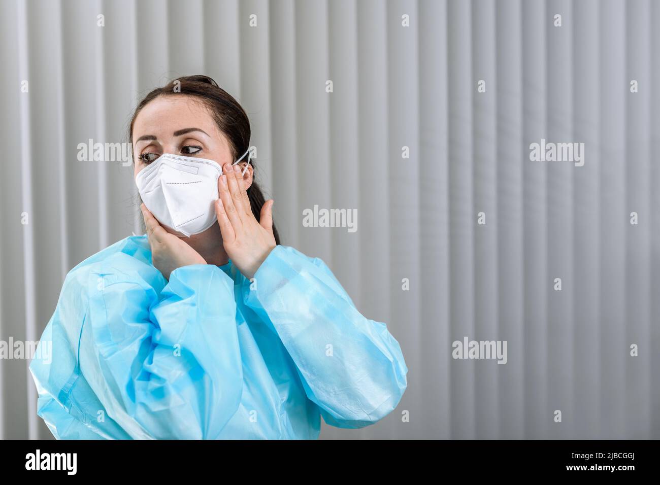 Female nurse adjusting N95 mask on her face in admissions office before ...