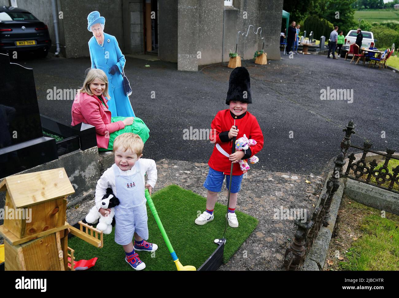 Laura McKnight holds a cardboard cut-out of Queen Elizabeth II as her sons Noah (5) and Louis (2) play mini golf at a picnic at St. Bartholomew's Parish Church, Newry, as part of the Big Jubilee Lunch as celebrations continue across Northern Ireland for the Queen's Platinum Jubilee. Picture date: Sunday June 5, 2022. Stock Photo