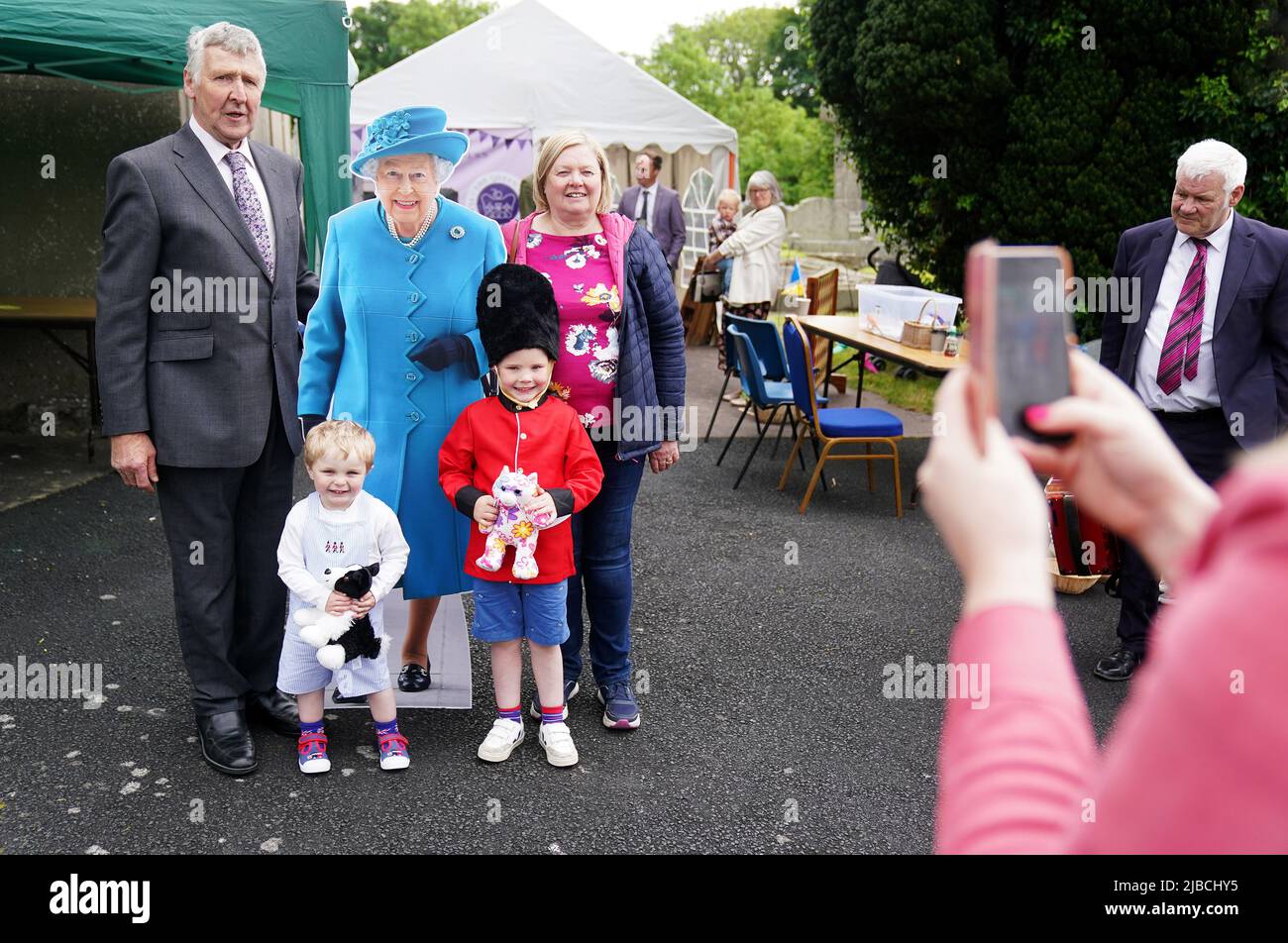 People pose for pictures with a cardboard cut-out of Queen Elizabeth II as they attend a picnic at St. Bartholomew's Parish Church, Newry, as part of the Big Jubilee Lunch as celebrations continue across Northern Ireland for the Queen's Platinum Jubilee. Picture date: Sunday June 5, 2022. Stock Photo