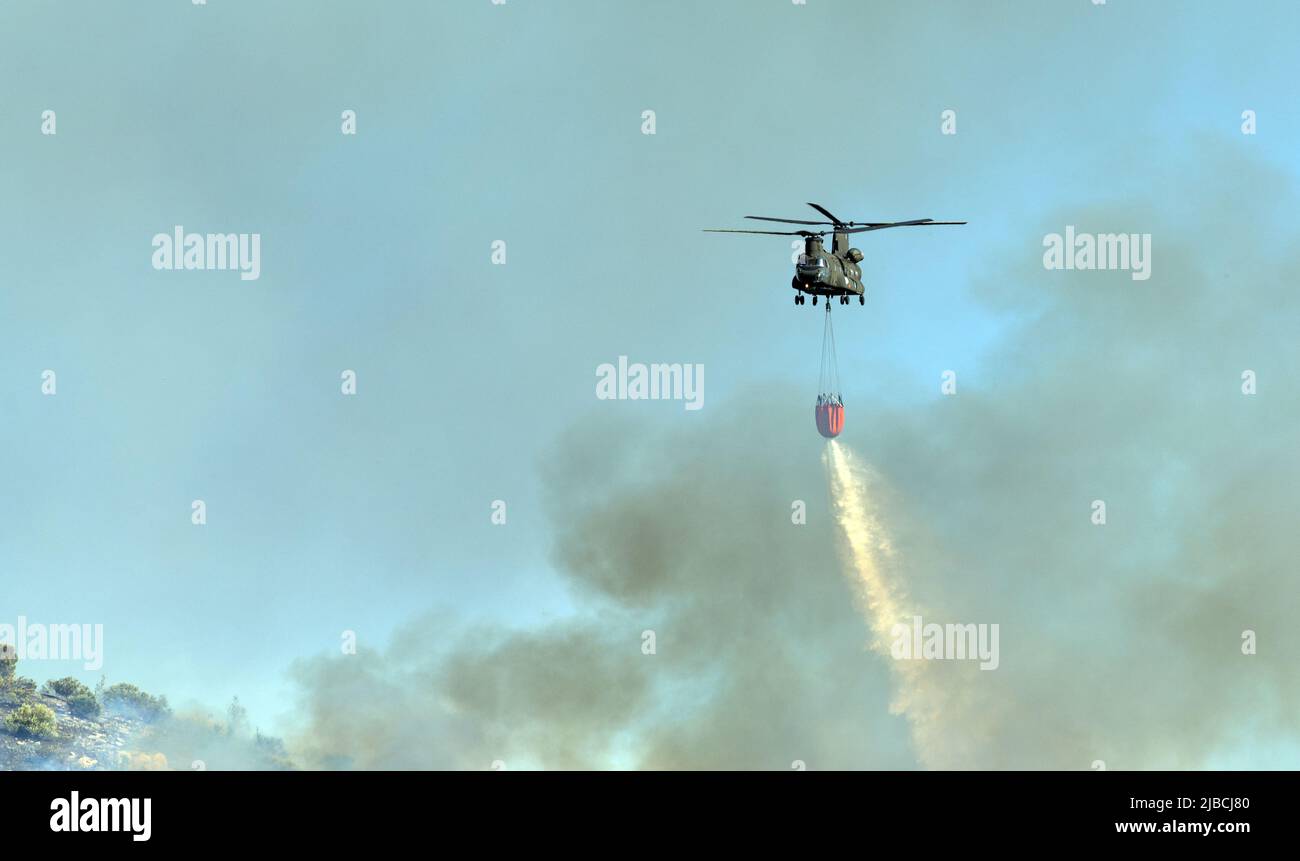 Athens, Greece, June 4, 2022: A firefighting Boeing CH-47D Chinook helicopter operates in Hymettus mount wildfire near Glyfada suburb of Athens. Stock Photo
