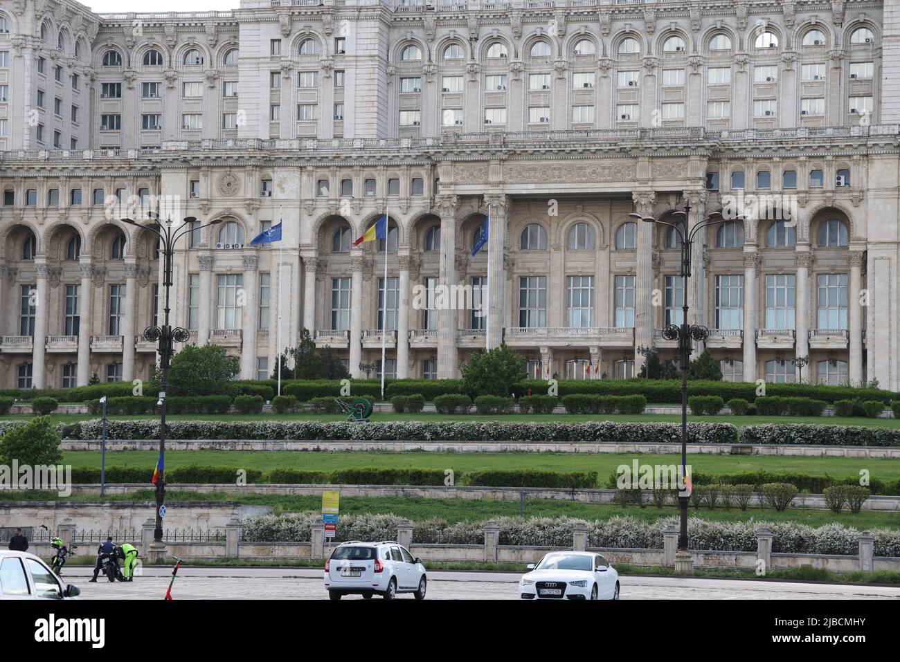 NATO, Romanian & EU flags in front of the House of the people in Bucharest, Romania; the 2nd largest building in the world. Seat of the parliament Stock Photo
