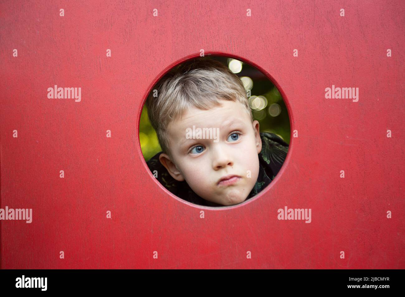 Funny boy looking through the hole on the playground.Copy space for