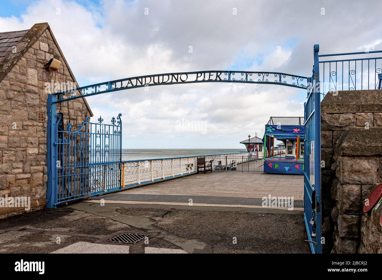 A wrought iron gate opens onto the decking of the 2295 ft Grade ll listed Victorian Llandudno Pier with its many interesting kiosks and amusements Stock Photo