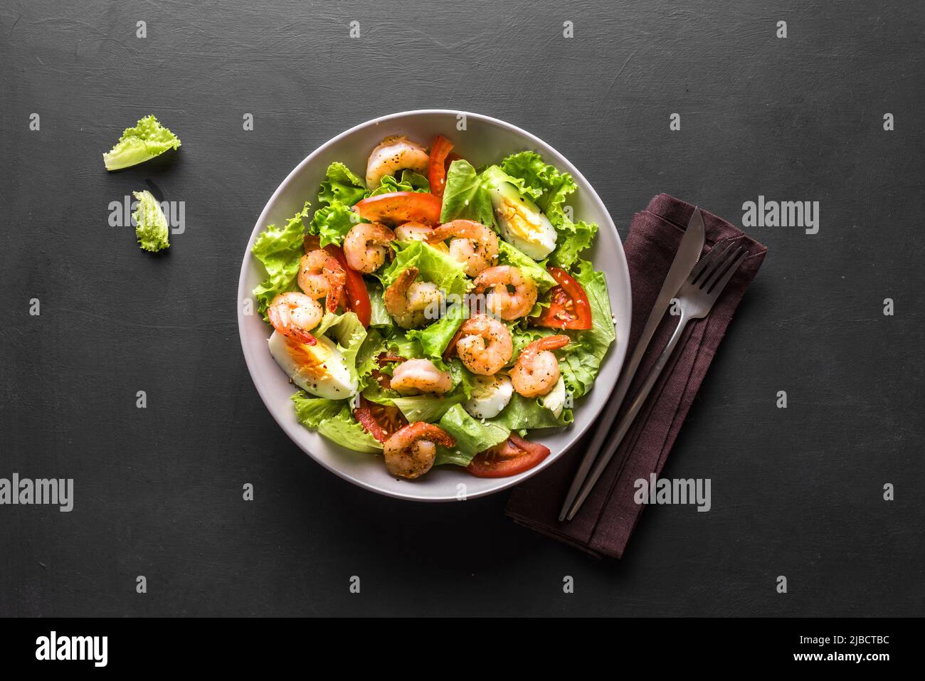 Shrimp Salad. Seafood Caesar Salad on black background, top view, copy space. Stock Photo