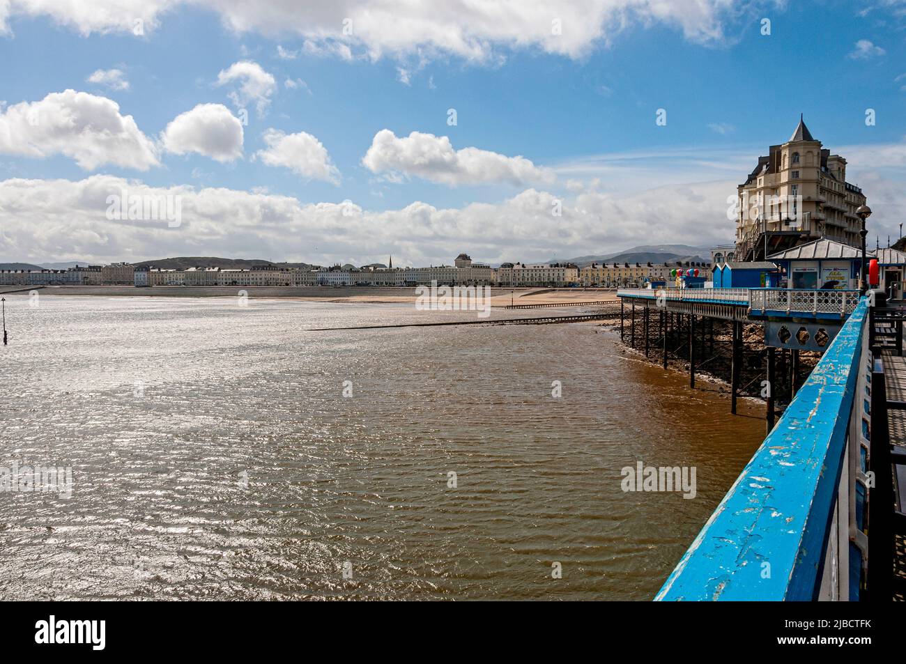 Looking back towards Llandudno from the Grade ll listed Victorian Pier to the mountains in the distance and the arc of hotels behind the sandy beach Stock Photo
