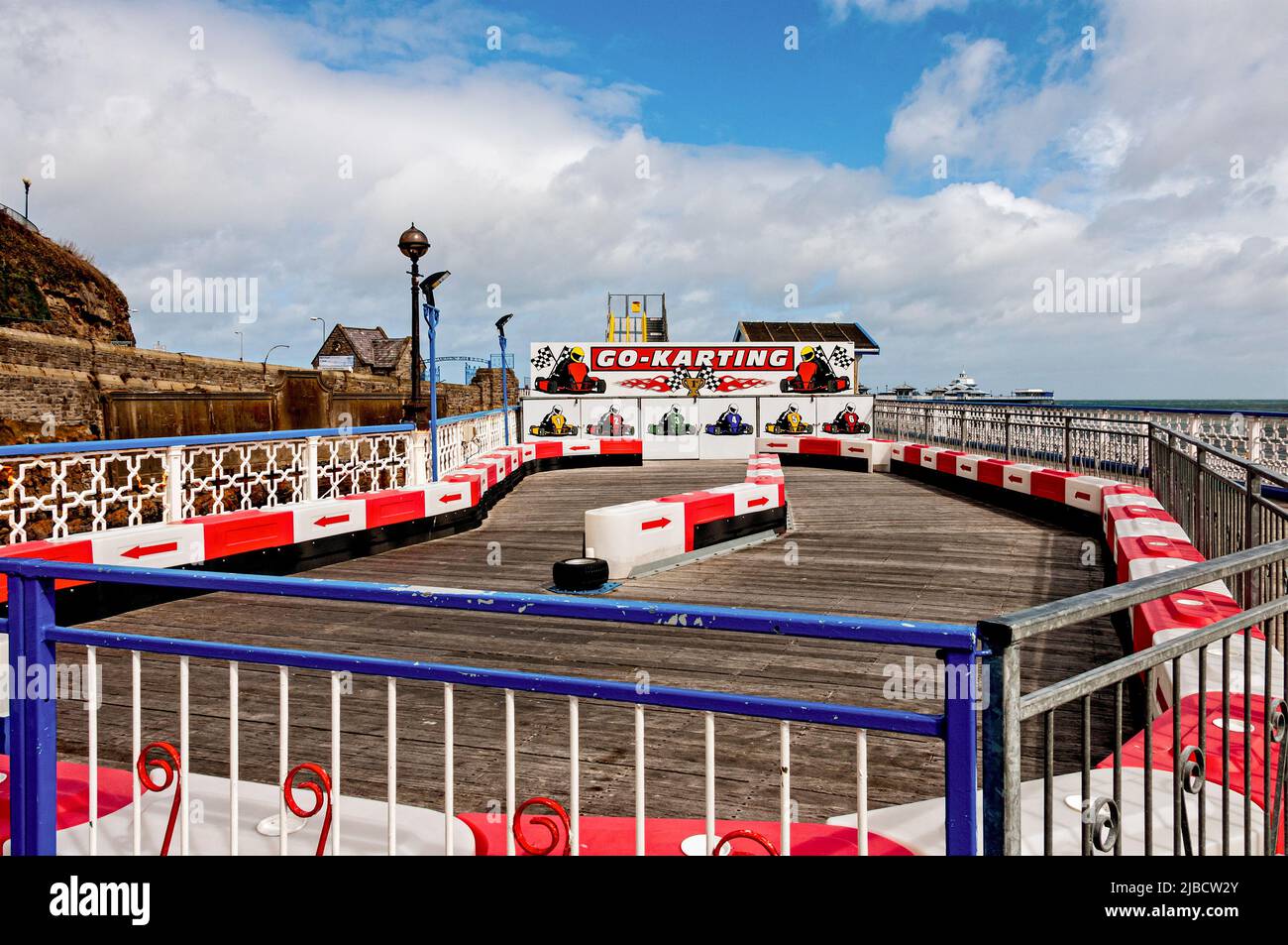 A red and white Go-karting track stands on the decking of the Grade ll listed Victorian Llandudno Pier with its many interesting kiosks and amusements Stock Photo