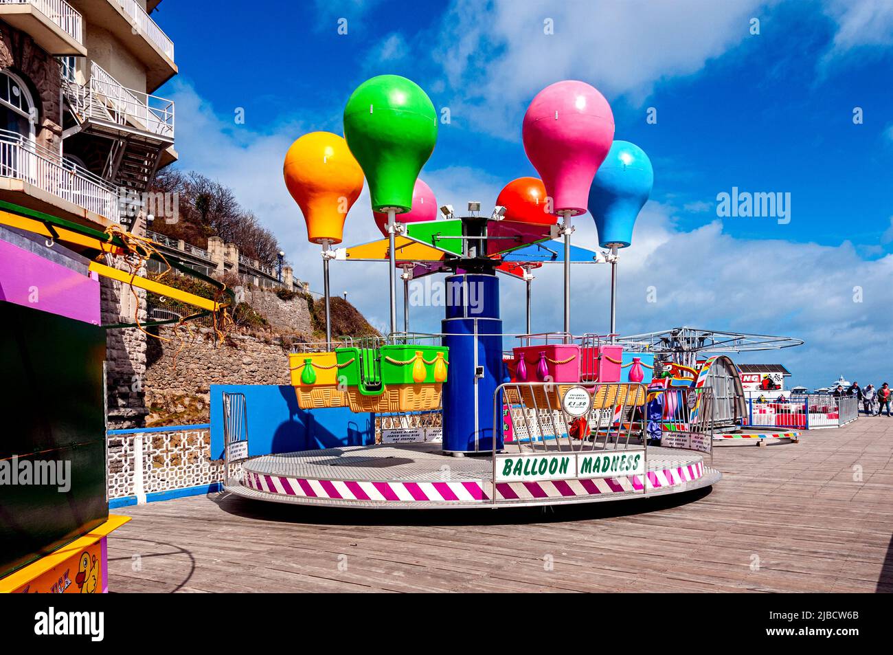 Vividly coloured plastic model balloons are used to attract customers to a ride on the Grade ll Listed Victorian Llandudno Pier completed in 1878 Stock Photo