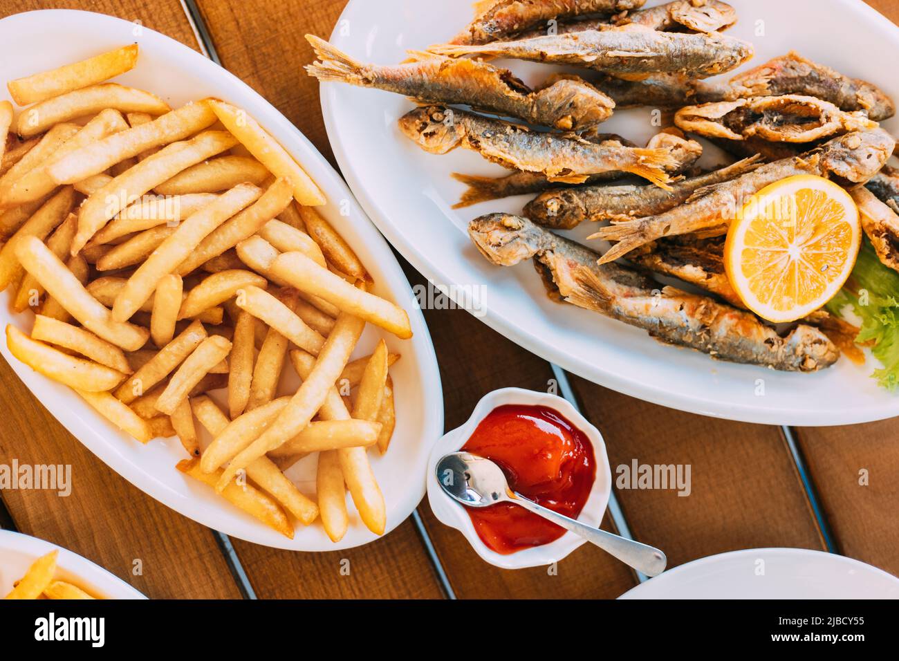 french fries and grilled fishes. fish and chips. Dish with Mullet Fish With orange. Fried fry small fishes Stock Photo
