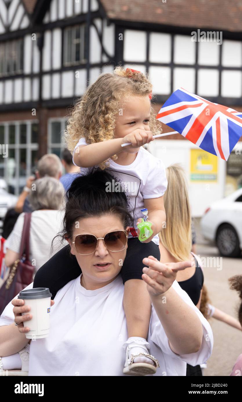 Young child waving a union jack flag sitting on mothers shoulders during the Queens Platinum Jubilee celebrations, Newmarket Suffolk UK Stock Photo