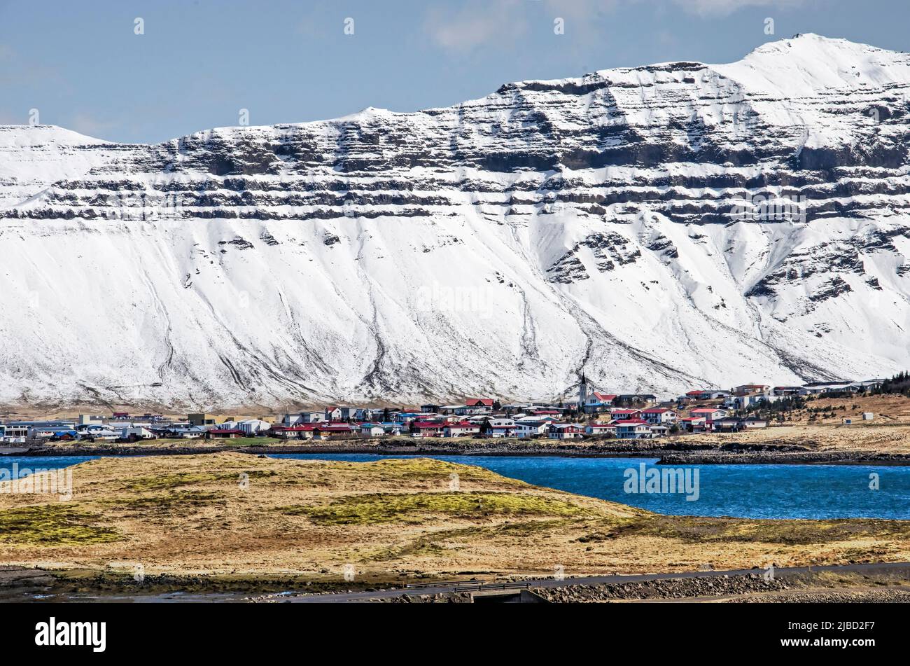 Grundarfjörður, Iceland, May 6, 2022: view across hills and bodies of water towards the town against a spectacular backdrop of snow-covered mountain s Stock Photo