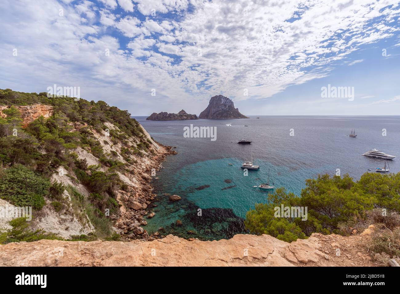 Super panoramic view Es Vedra rock on horizon and piercing blue summer sky full of ragged small white clouds, Ibiza, Balearic Islands, Spain Stock Photo