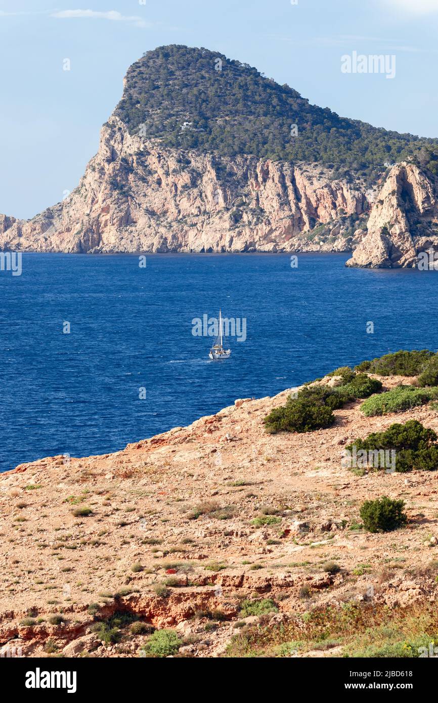 Sailing yacht on bright blue water of Mediterranean Sea against the backdrop of a rearing headland of Cap Nuno (Nono), Ibiza, Balearic Islands, Spain Stock Photo