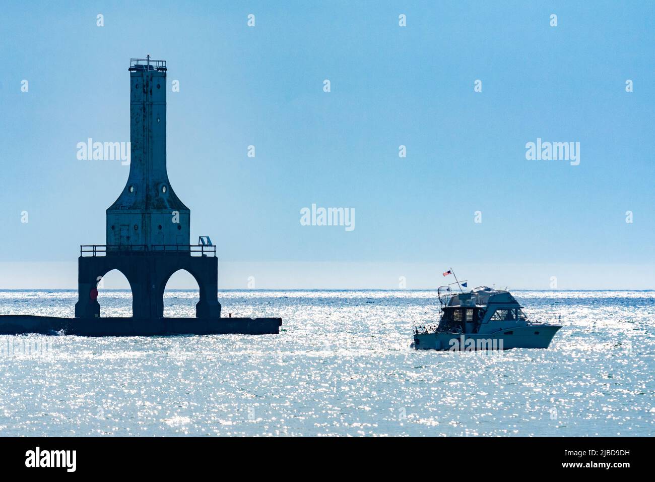 An unidentified boat passes close to the Port Washington Break Water Light in Port Washington, Wisconsin on a summer's morning. Stock Photo