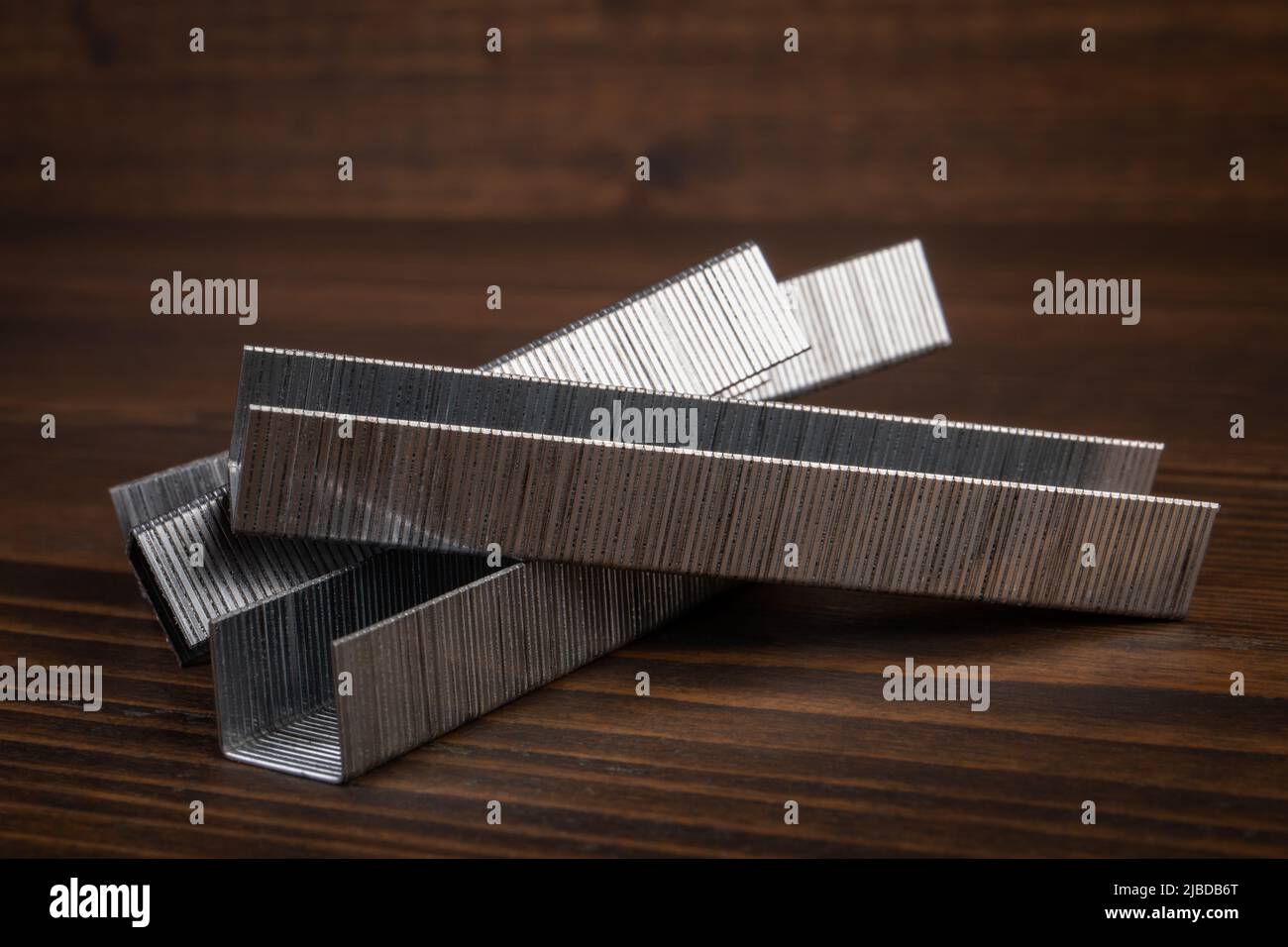 Metal staples for staple guns on a wooden texture background Stock