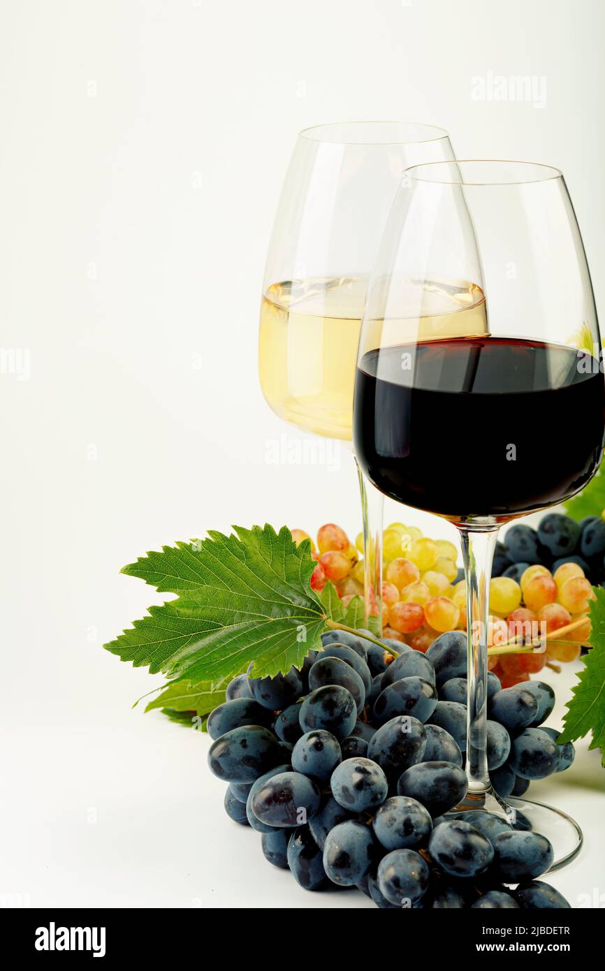 A glass of white wine, a glass of red wine, fresh grapes and grape