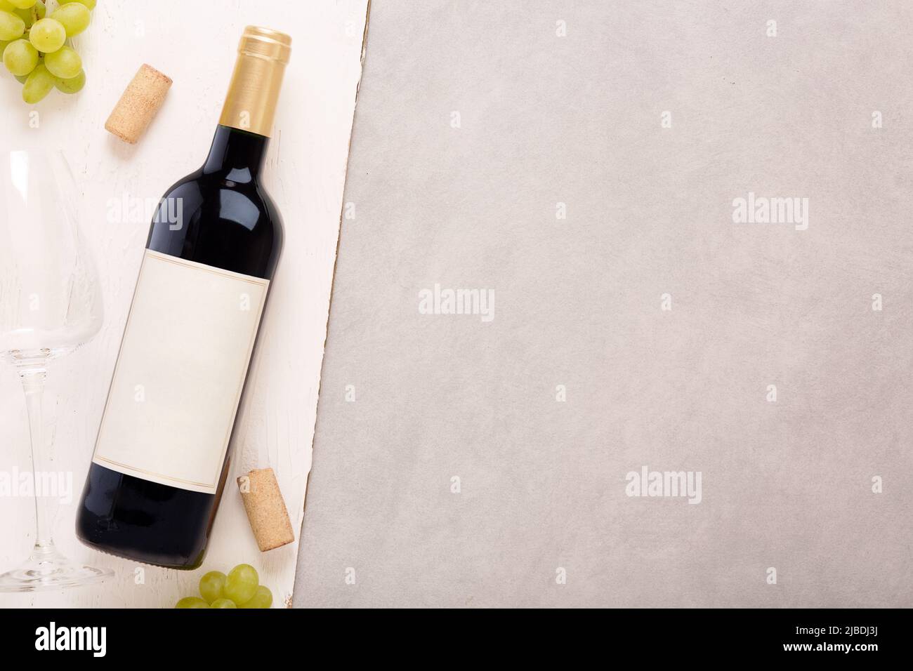 Bottle of white wine with label. Glass of wine and cork. Wine bottle mockup. Top view. Stock Photo