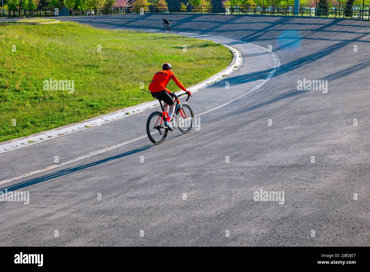 A cyclist with red jerseys on the cycle-racing track for training. Healthy lifestyle or bicycling or training concept photo. Motion blur on the cyclis Stock Photo