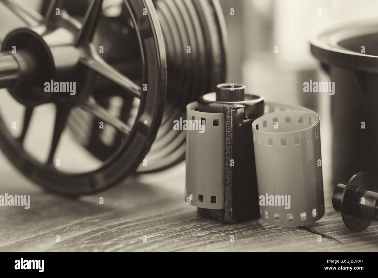 Photo film roll and cassette, photographic equipment - developing tank with its film reels on background. Selective focus. Retro black and white photo Stock Photo