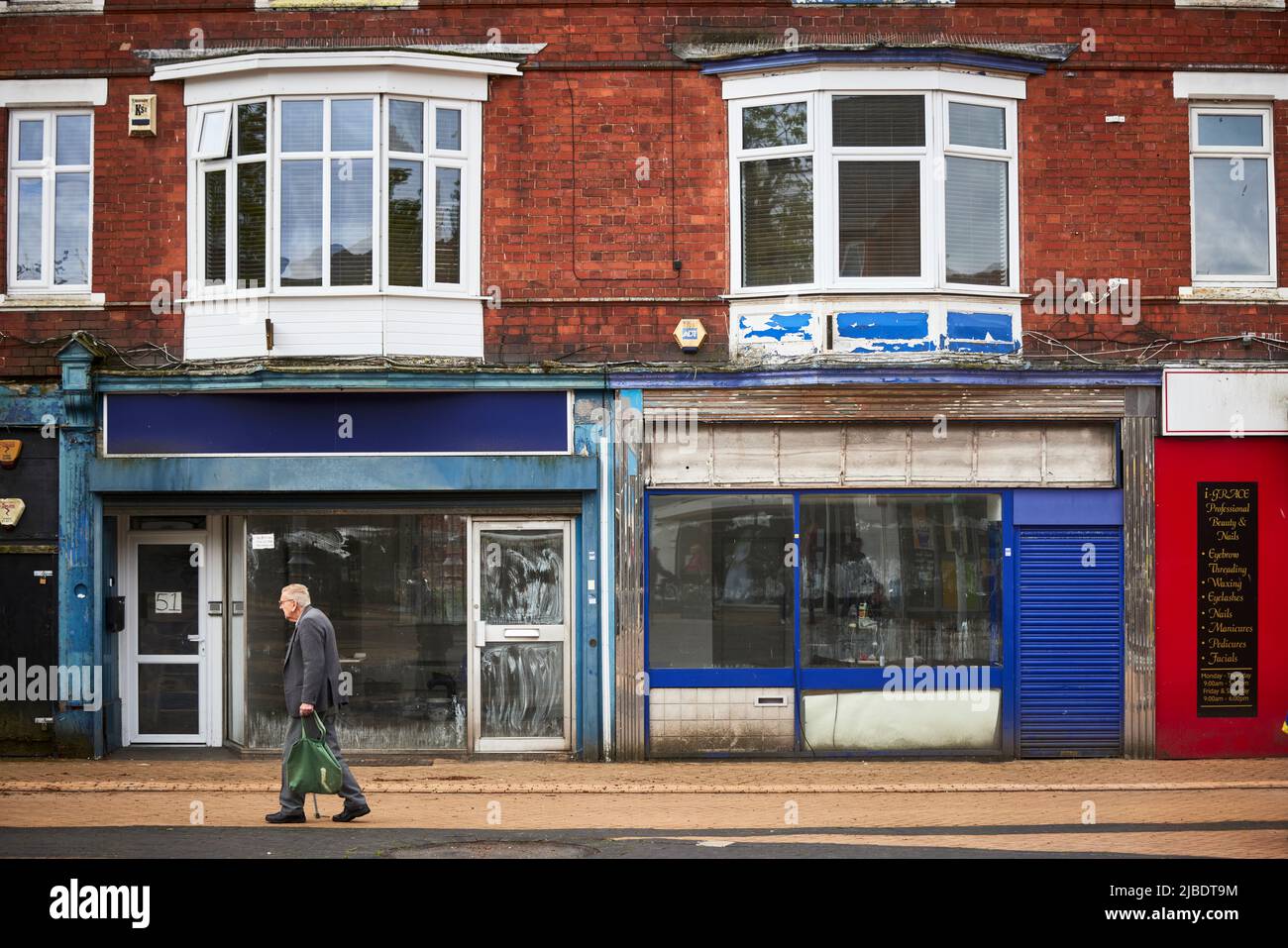 OAP man walking past Sutton-in-Ashfield is a market town in Nottinghamshire near  Mansfield closed down shops in the town centre Stock Photo