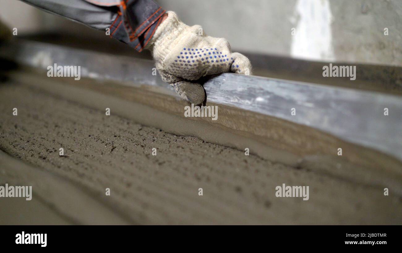 The worker pours the floors with mortar. The builder is working on
