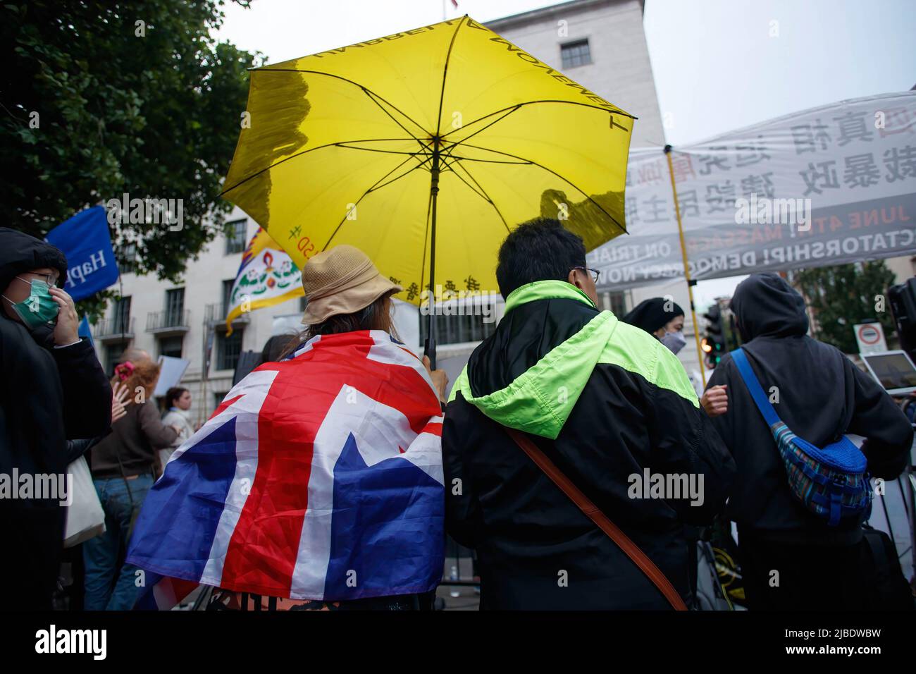 A demonstrator holds a yellow umbrella while wearing a British Union Jack flag during the Tiananmen Remembrance Vigil Rally to mark the 33rd anniversary of the 1989 pro-democracy movement and the Tiananmen Square massacre, outside the Chinese Embassy in London. (Photo by May James / SOPA Images/Sipa USA) Stock Photo