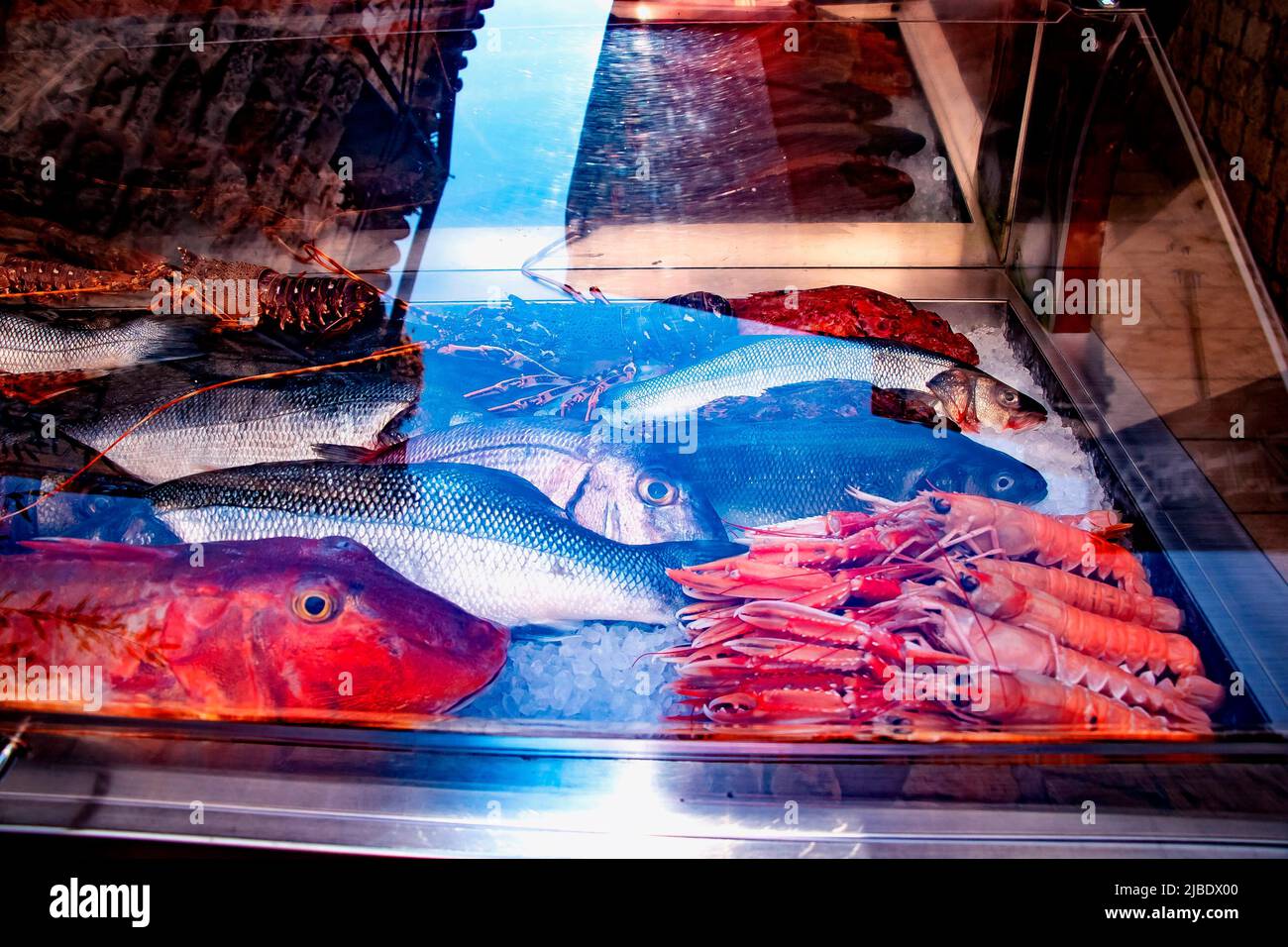 Close up fresh shrimps and fishes on display on ice on fishermen market store shop. Seafood is an important part of Croatian cuisine. Stock Photo