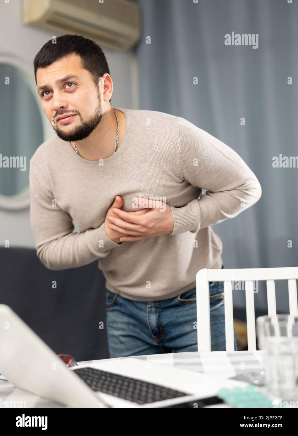 Young man having heart pain and feeling unwell at home Stock Photo