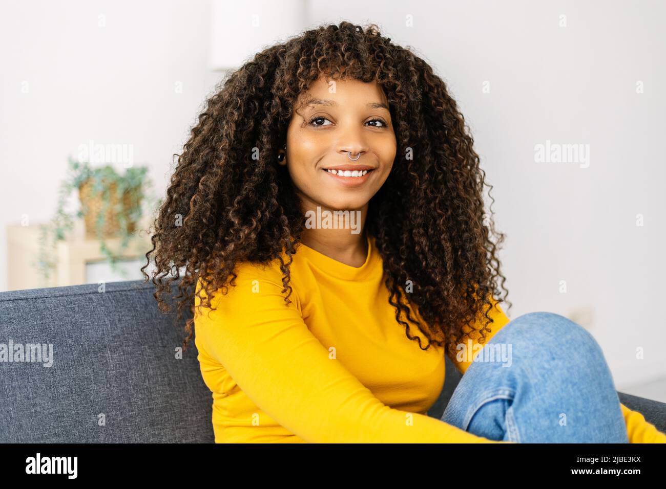 Happy young african american woman sitting on couch at home Stock Photo ...
