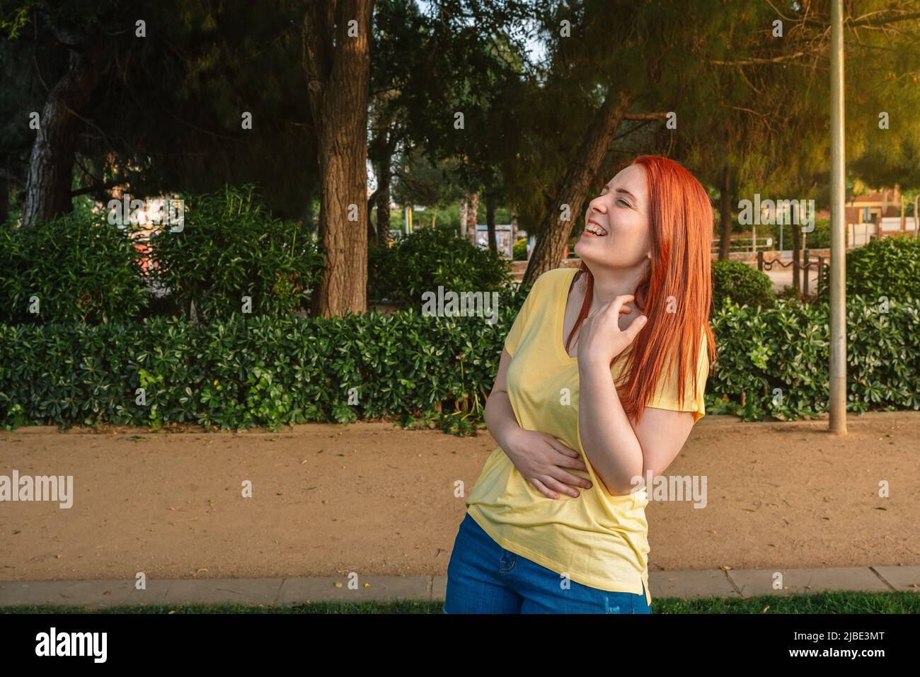 young redhead girl laughing out loud in a public park. woman enjoying the weekend or her summer holiday. Stock Photo