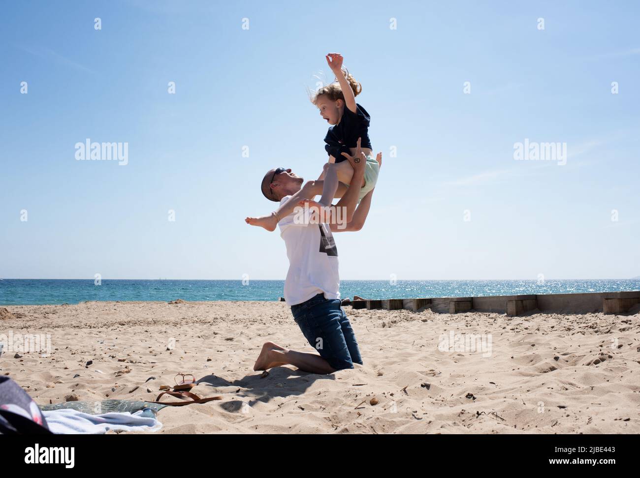 father throwing his child up in the air on a sunny day at the beach