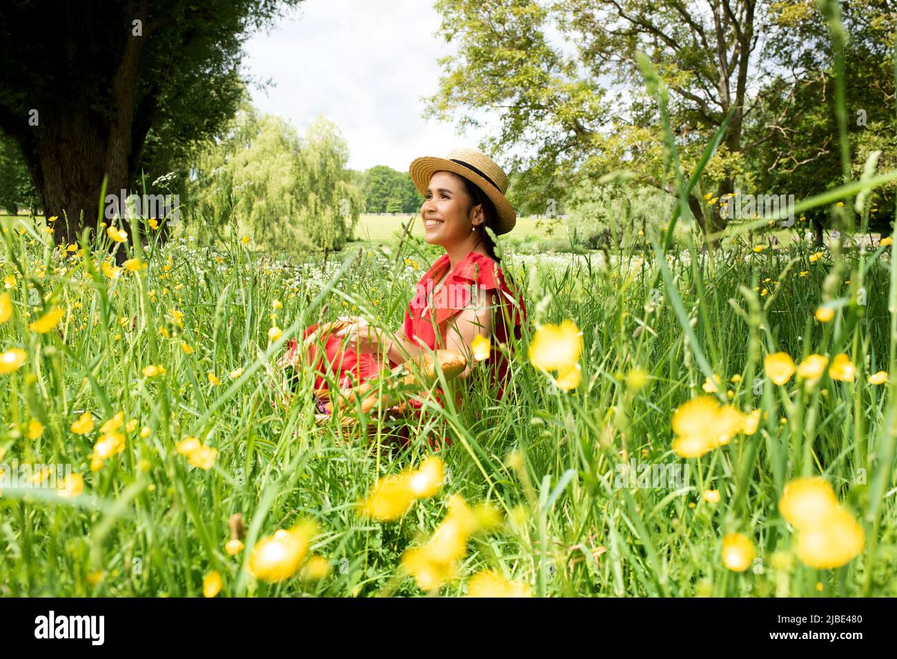 portrait of beautiful Asian woman sat in a field enjoying the sunshine Stock Photo