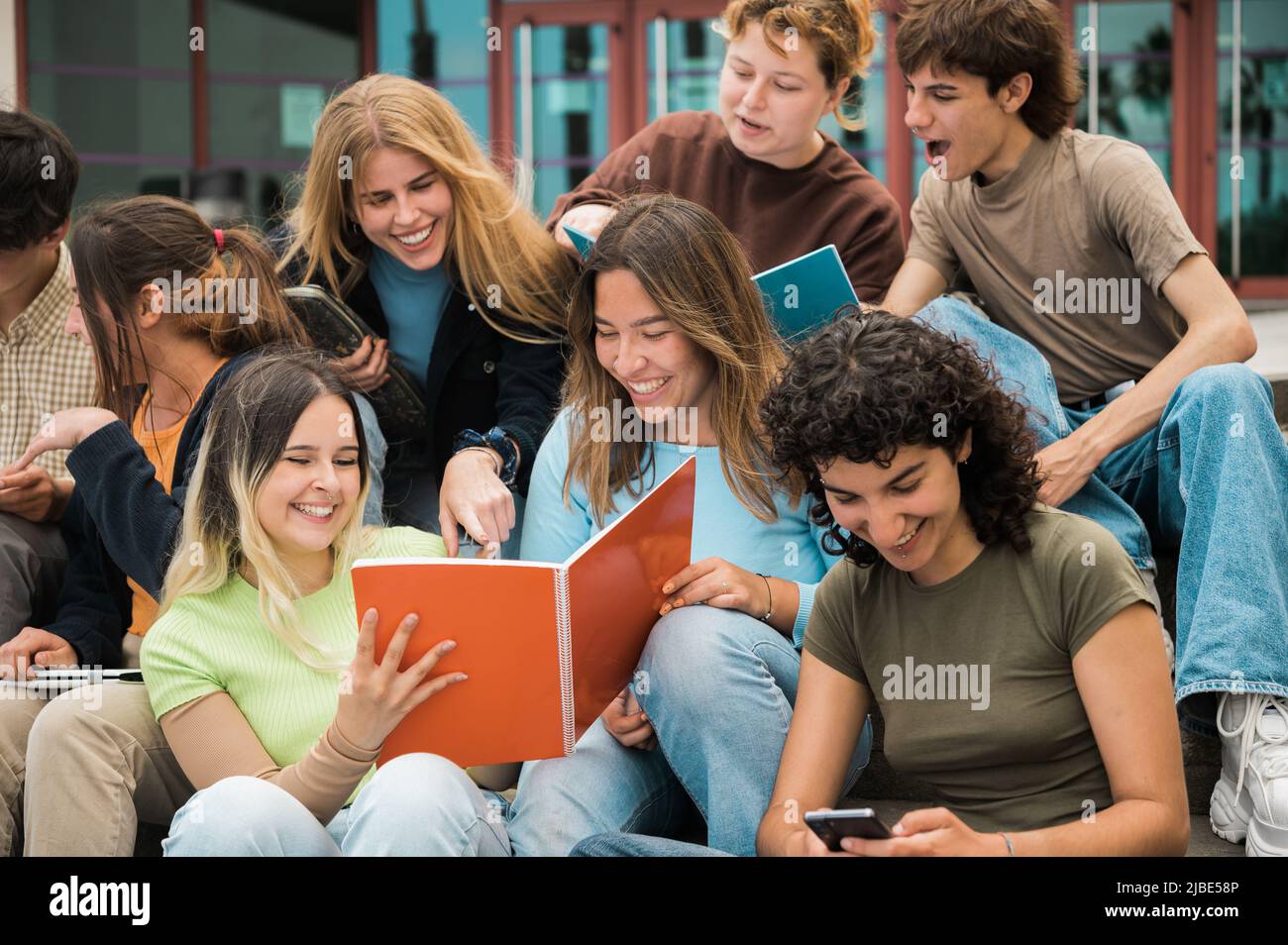 Delighted multiracial students reading notes and smiling on stairs Stock Photo