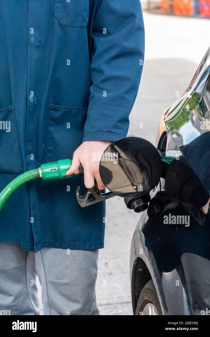 Filling station attendant dispensing unleaded fuel into a car on the forecourt. Close view. Attendant service is rare in the UK nowadays Stock Photo