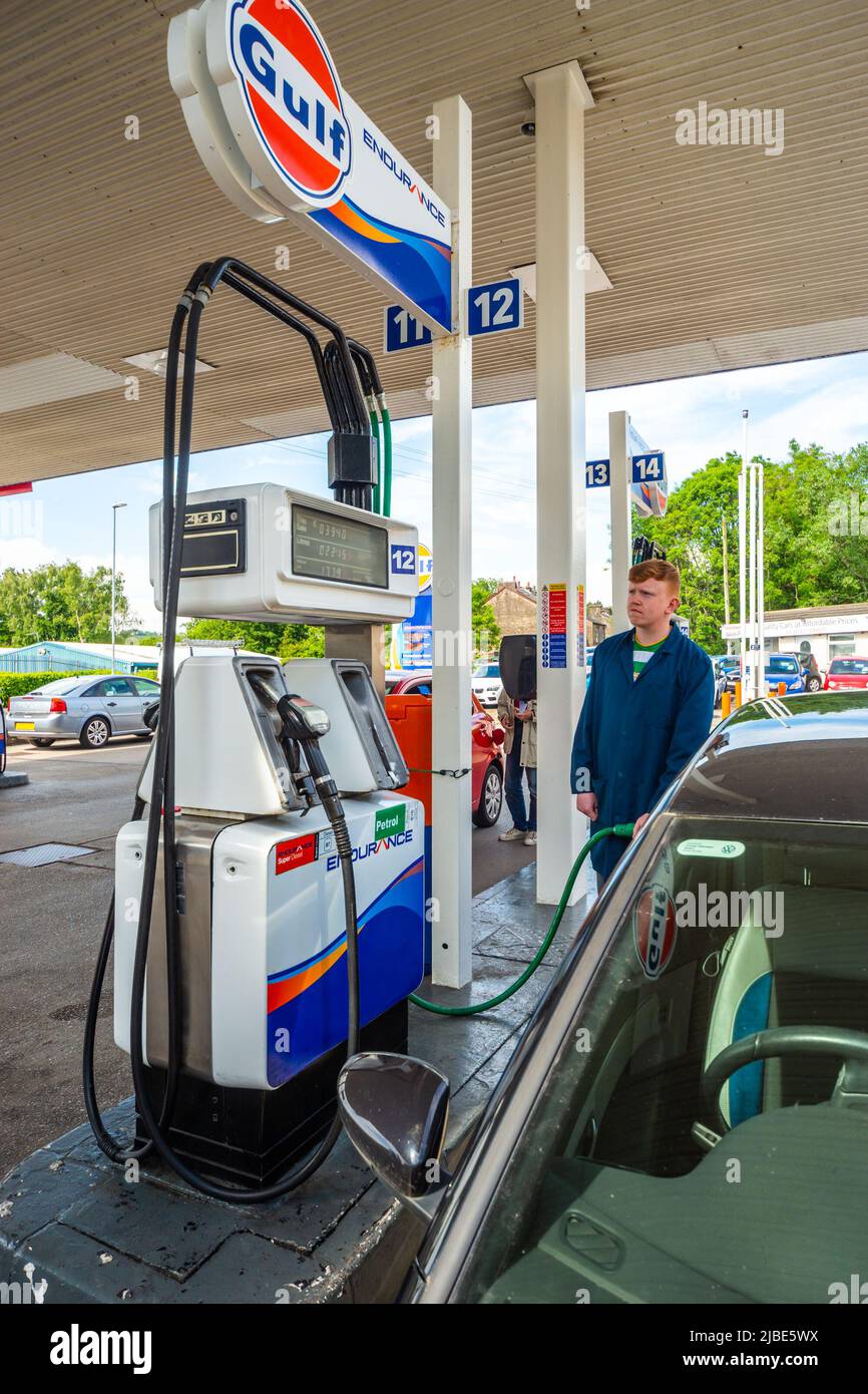 Filling station attendant dispensing unleaded fuel into a car on the forecourt. Wide view of pumps. Attendant service is rare in the UK nowadays Stock Photo