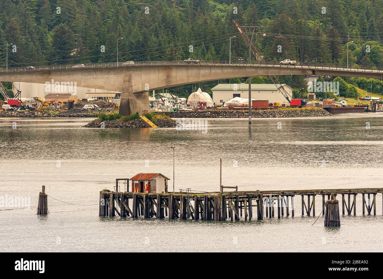 Juneau, Alaska, USA - July 19, 2011: Concrete bridge over Gastineau Channel with cars on top and construction site behind. Gray ocean water up front a Stock Photo