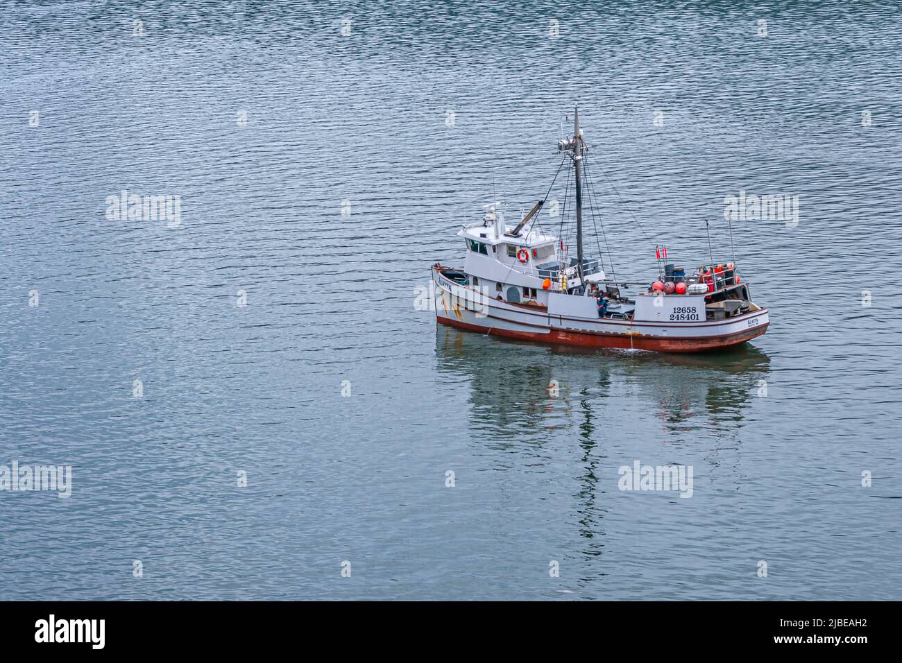 Juneau, Alaska, USA - July 19, 2011: Closeup of red-white Alrita fishing vessel out of Seattle on gray-blueish Gastineau Channel water. Portective bal Stock Photo