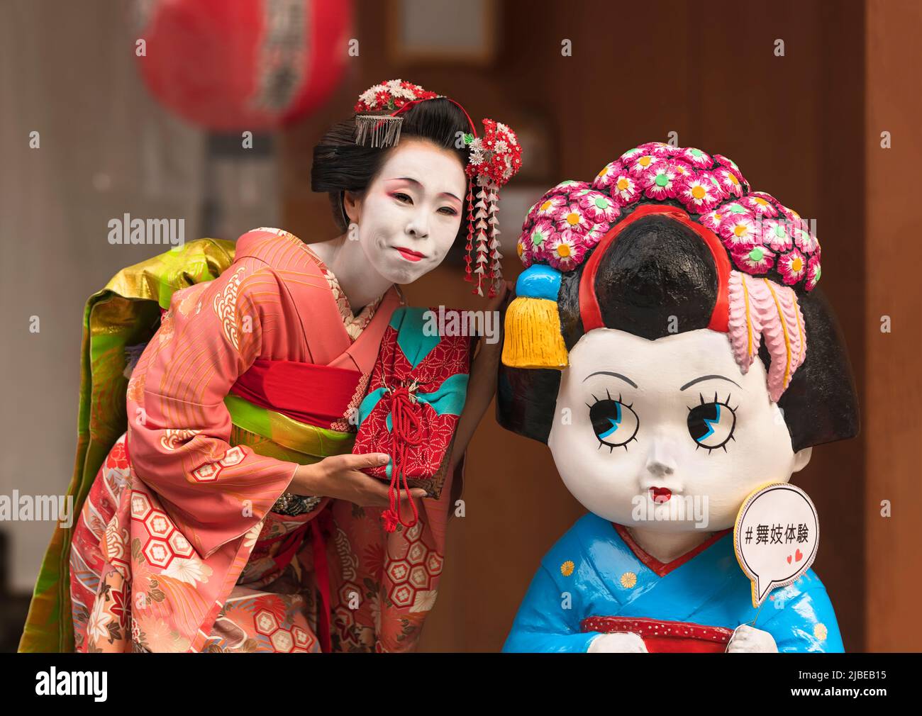 kyoto, japan - march 26 2018: Japanese female posing in a Maiko's outfit aside a character depicting a maiko with a speech balloon where is wrote the Stock Photo
