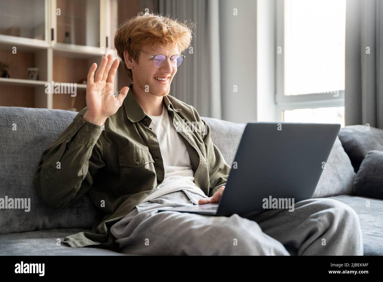 Smiling ginger irish man having video call over laptop computer at home Stock Photo